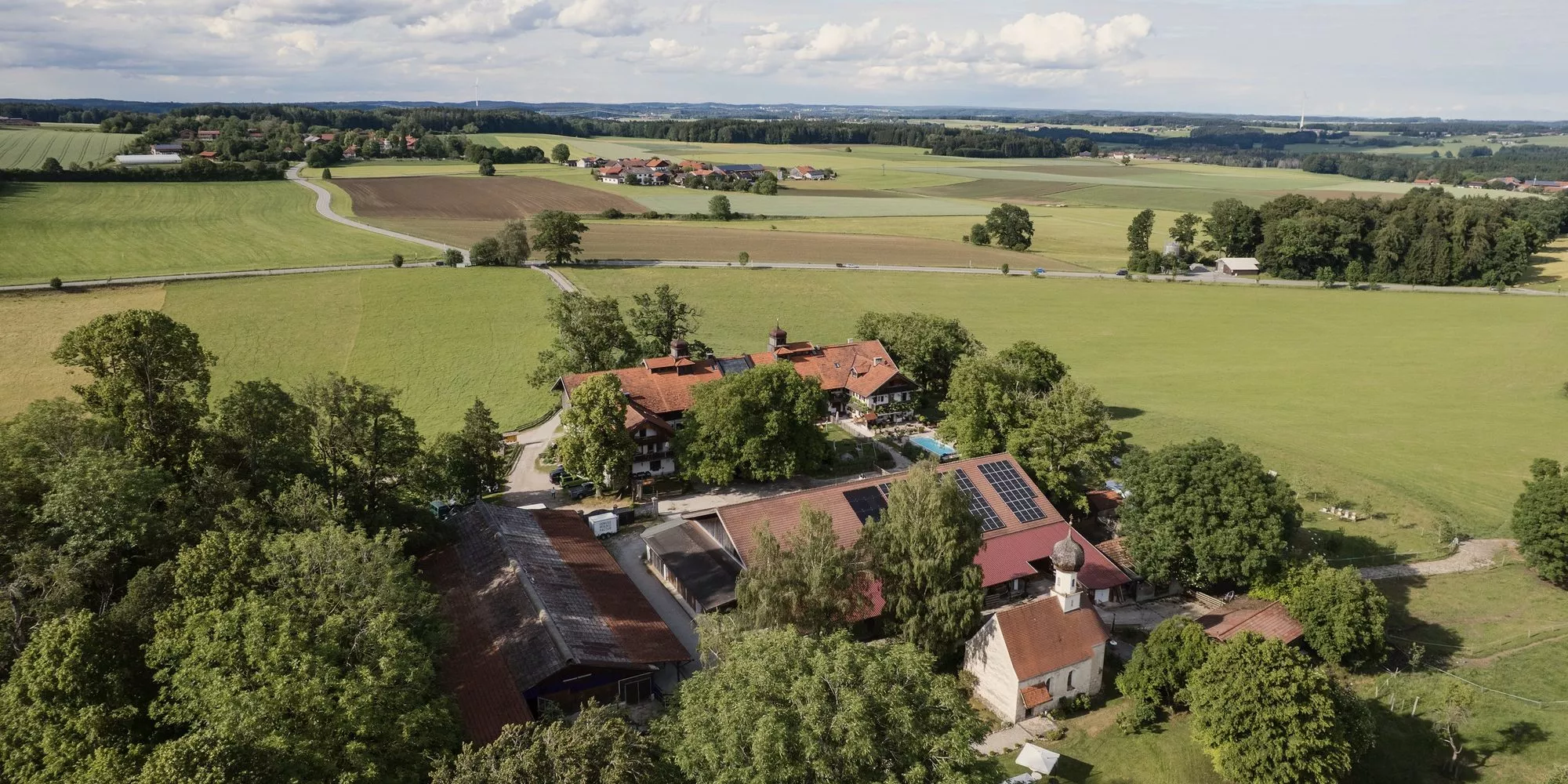 Gut Georgenberg von oben, mit Kirche, Hofgebäuden und Feldern ringsum.