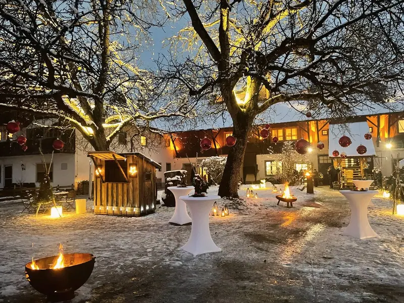 Der kleine Weihnachtsmarkt im Innenhof am Abend, mit Feuerschalen und Lichtern.